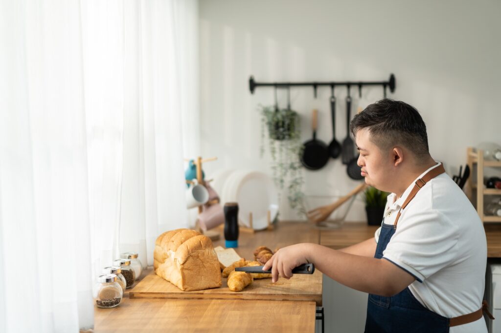 Asian young man with down syndrome baking bakery in kitchen at home.